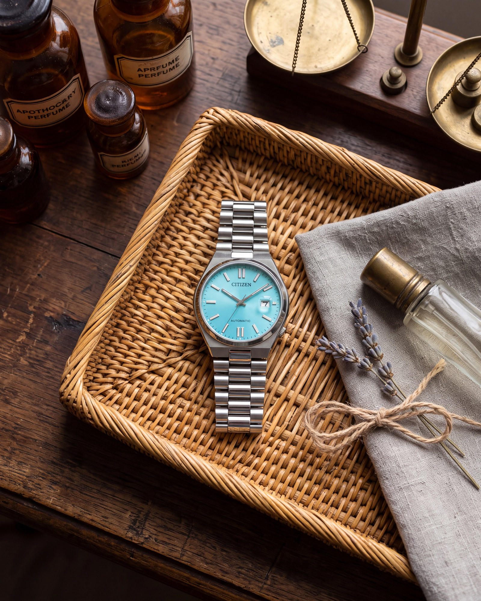 Montre Citizen Tsuyosa NJ0151-88M posée sur un plateau en osier, avec cadran bleu turquoise, bracelet en acier inoxydable argenté, près de flacons ambrés et de lavande.