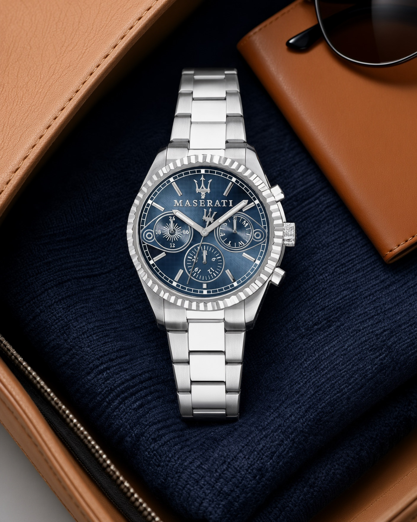 Maserati Competizione R8853100013 stainless steel watch with a blue dial, lying on a navy sweater inside a tan leather travel bag